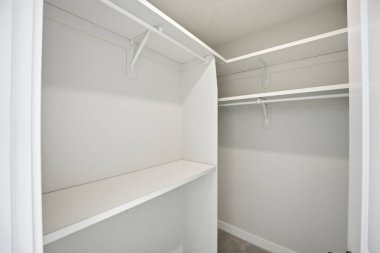 Rafları ve beyaz kapısı olan beyaz bir dolap. Dolapta hiç kıyafet yok.