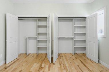 İki dolabı olan büyük, boş bir oda. Biri solda, biri sağda. Dolaplar açık, raflar ve dolaplar giysi ve diğer şeylerle dolu. Oda temiz.