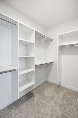 Raflı ve askılı beyaz dolap. Dolap boş ve duvarlar beyaz.