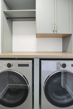 Gümüş LG kurutma makinesi ahşap tezgahın yanında duruyor. Tezgah tahtadan yapılmış ve açık renkli.