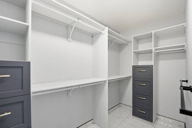 Beyaz duvarları ve gri çekmeceleri olan küçük bir dolap. Dolap boş ve giysisi yok.