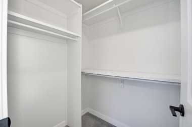 Siyah kapılı beyaz dolap. Dolap boş ve rafı var. Kapı kapalı.