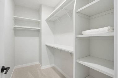 Rafları ve siyah kapısı olan beyaz bir dolap. Dolap boş ve temiz. Dolabın beyaz rengi sakinlik ve basitlik hissi veriyor.