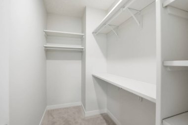 Rafları ve beyaz masası olan küçük beyaz bir dolap. Dolap boş ve raflar boş.