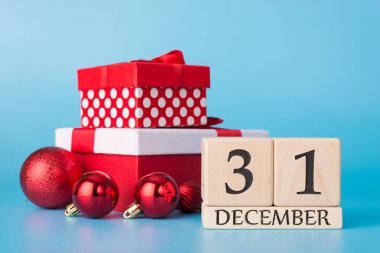 Mutlu yeni yıl kutlamaları. Parlak mavi arkaplan üzerine izole edilmiş 31 Aralık tarihli parlayan tişört oyuncakları ve takvimin sarılı olduğu fotoğraf yığınını kapat