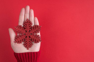 Yukarıdaki tepede pov 'un üstünde kadın eli olan ilk kişinin canlı renk arkaplanı üzerinden izole edilmiş büyük, ışıl ışıl kar tanelerini gösteren boş bir dokuyu taklit ederken çekilmiş fotoğrafı var.