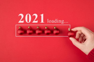 Tatil konseptini bekliyorum. Kesilmiş yakın plan fotoğraf küçük oyuncak ağaç topu tutarken parlak kırmızı arkaplan üzerine izole edilmiş bir çizgi koyuyor