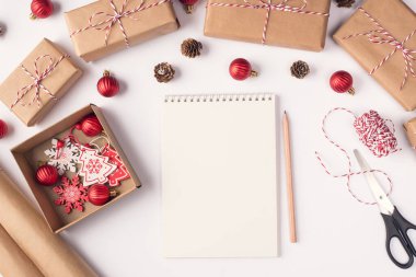 Yukarıdaki boş defterin ve masadaki hediyeleri paketlemek için kullanılan aksesuarların yakın plan fotoğrafı.