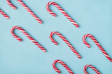 Pastel rengi mavi arkaplan üzerinde köşegen halinde uzanan parlak, lezzetli, karamelli sert şekerlerin yakın plan fotoğrafı.