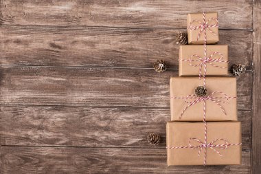Kraft kağıdına sarılı hediye kutuları yığını fotoğrafı. Ahşap arka planda kırmızı ve beyaz ip sicimle bağlanmış.