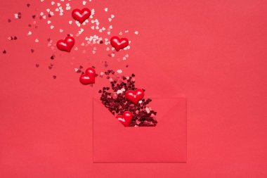 Romantik duygular ifade etme konsepti. Paketlenmemiş kağıt zarfın düz resmi ve uçup giden parlak parıltılı parıltı ve parlak arkaplandaki kalpler