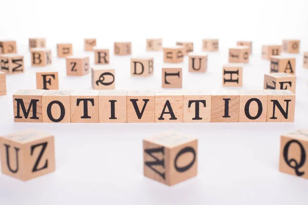 Motivation concept. Close up view photo of wooden cubes making showing word motivation on white background