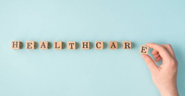 Sağlık sigortası konsepti. Pov yakın plan kadın eli son tahta bloğu bir çizgi içine koyarak kelime sağlık hizmetleri izole pastel arkaplan