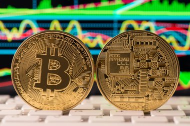 Klavye tuşları üzerinde duran parlak grafikle arka ve ön tarafları gösteren altın bitcoin fotoğrafını kapat