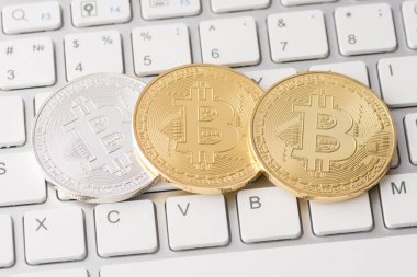 Beyaz klavye tuşları üzerinde duran altın ve gümüş bitcoin 'in yakın plan fotoğrafı