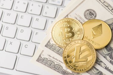 Bitcoin ethereum ve litekoin 'in altın sikkelerinin yakın plan fotoğrafı Amerikan parası ve beyaz klavye üzerine yatar.