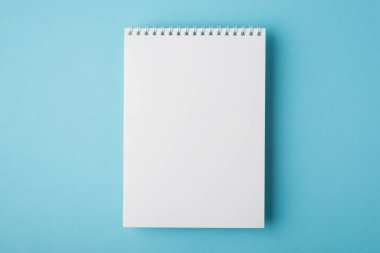 Düz tepenin üzerinde, izole edilmiş harf belgesi için açık spiral not defterinin yakın görünüm fotoğrafı uzanıyordu.