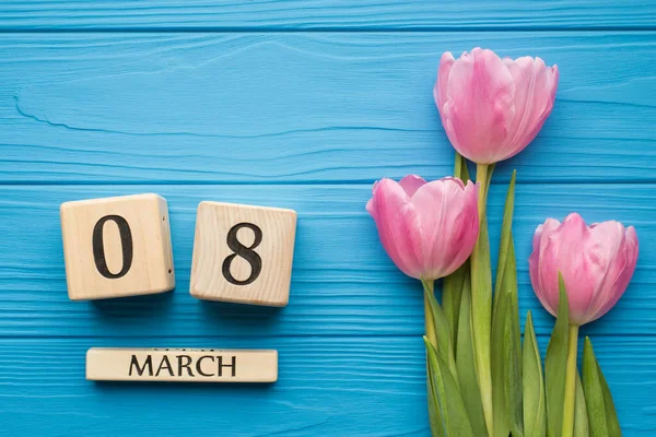 Happy international women\'s day concept. Fla lay close up top overhead view photo of pink tender tulips and block shape calendar showing the date isolated bright color desk