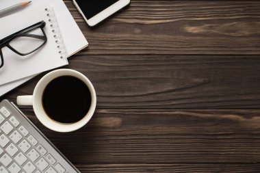 Çalışanların iş yeri konsepti. Yukarda düz bir görünüm üzerinde gözlük fotoğrafı kalem planlayıcısı akıllı telefon klavyesi ve izole edilmiş koyu kahveden bir fincan koyu kahverengi fon.