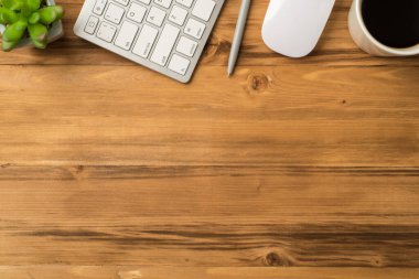 Ofis eşyalarının yukarıdaki resmi. Klavye, gri kalem, fare fincanı. Açık ahşap zeminde sulu.