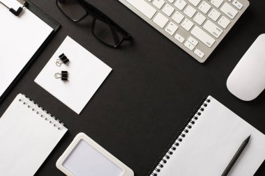 Üst katta ofis malzemelerinin yukarıda duran resmi nesnelerin bilgisayar nesneleri faresiz kağıt kopya kitapları boş boş aralıklı gözlükler tasarım metni için izole edilmiş siyah zemin