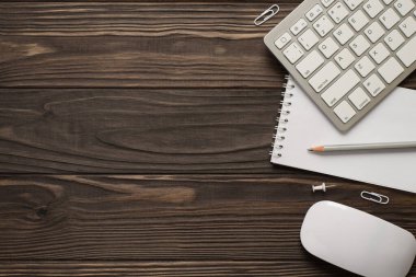 Tepede beyaz renkli klavye dizüstü bilgisayar faresi resmi ve izole edilmiş koyu kahverengi tahta arka plan iğneleri var.