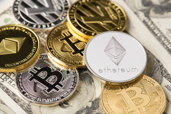 Вверху вверху вверху фотографии много разных золотых и серебряных криптовалют, лежащих на стопке американских долларов