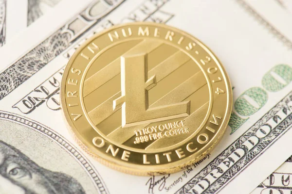 Yukarının üstünde altın litekoin 'in Amerikan banknotlarının üzerine serilmiş fotoğrafı var.
