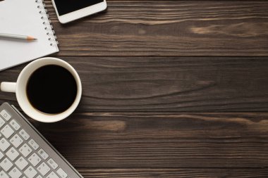 Ofis aksesuarlarının, şirket planlamacılarının, cep telefonlarının, cep telefonlarının, klavyenin, koyu desenli arka planının üstünde resmi.