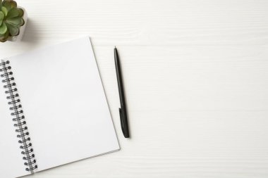 Net sayfalar ile sarmal üzerinde açık not defterinin düz görünümü ve kompozisyon yazmak için siyah kalem kopya alanı ile izole edilmiş beyaz ahşap zemin