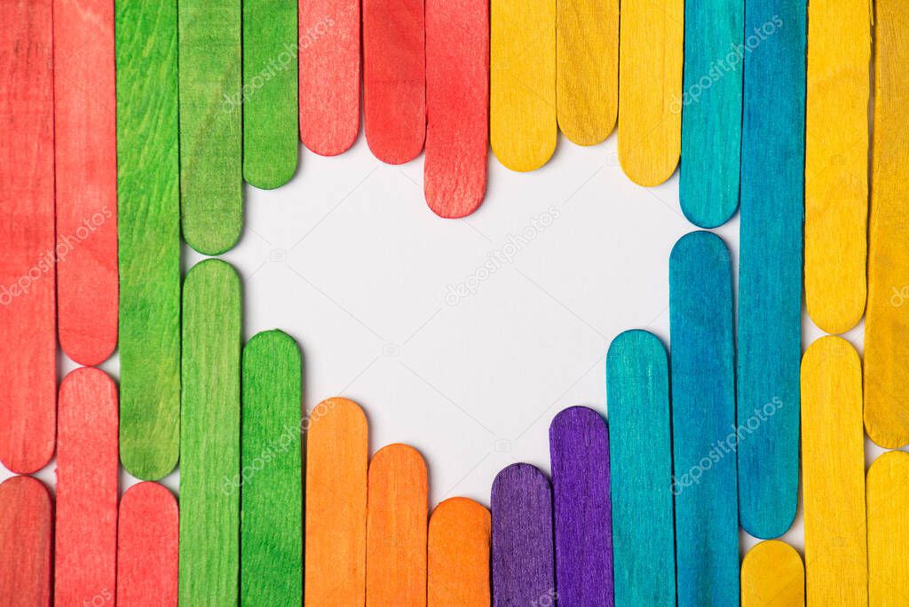 Lgbtq concept. Photo of white heart with empty space inside made of multicolored rainbow wooden sticks