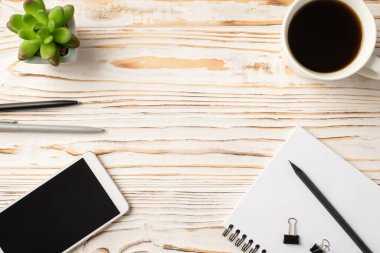 Tepede çiçek saksısı dijital telefon kalemi ve defter boş arkaplan ile izole edilmiş beyaz ahşap zemin