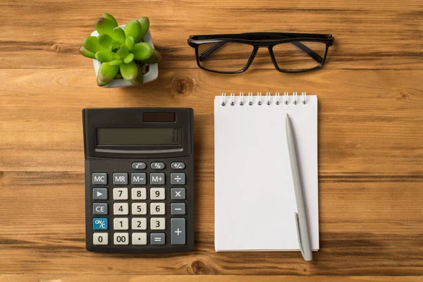 Budget for the next year concept. Flat lay above overhead close up view photo of blank notebook eyeglasses calculator flower isolated light color brown backdrop