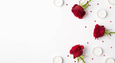 Beyaz arka planda izole edilmiş gül kalpli mumlar ve konfetiler.