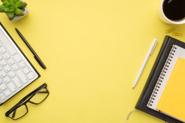 Klavye, kalem, bardak, kahve, ataç ve sarı arka planda izole edilmiş defter.