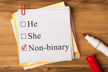 İkili olmayan kavram. Tahta arka planda izole edilmiş ataçların ve işaretleyicilerin fotoğrafı