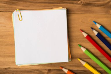 Kağıt ataçların ve ahşap arka planda izole edilmiş çok renkli kalemlerin fotoğrafı