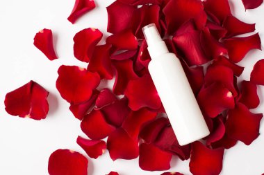 Beyaz arka planda izole edilmiş gül spreyi şişesi ve taç yaprakları.