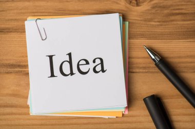 Sözcük fikri ve tahta masa arkaplanındaki siyah kalemli çıkartma notlarının en üstteki görünümü