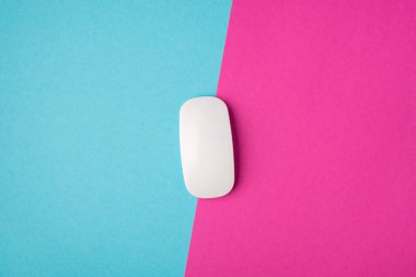 İzole edilmiş iki renk pembe ve mavi arkaplan üzerinde ortasında beyaz fare olan masaüstü fotoğrafının telif alanı ile üst görünümü