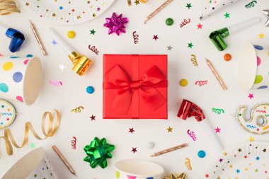 Fincanların üzerindeki konfeti tabağı hediyesi kırmızı kutu yayları ve beyaz arka planda izole edilmiş parti düdüğü.