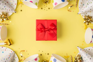 Kafamızın üstünde fincanların fotoğrafı kokteyl tabağı şapkası kanepe kanepe mum konfeti kırmızı kutu sürpriz ve sarı arka planda ıslık.