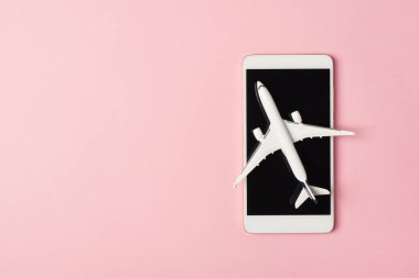 Akıllı telefondaki beyaz uçak modelinin üst görüntüsü izole edilmiş pastel pembe arka planda kopyalanmış