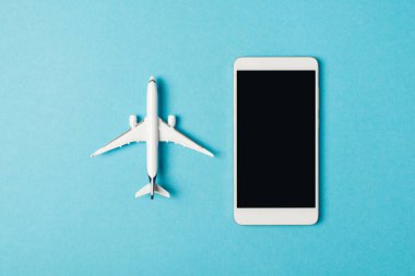 Mavi arka planda izole edilmiş akıllı telefon ve uçak fotoğrafı.