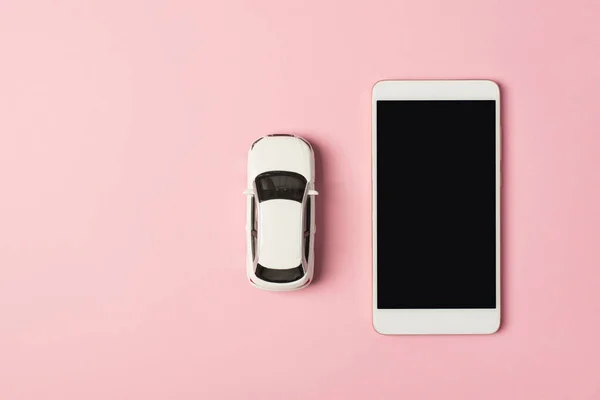 Above photo of white car and mobile phone isolated on the pink background
