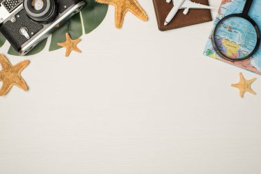 Pasaport kapağı üzerinde kamera haritası büyüteç uçak modeli ve izole edilmiş ahşap arka planda yıldızbalığı fotoğrafı.