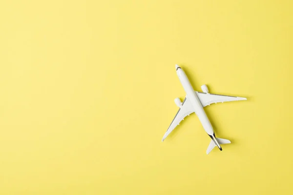 Top view photo of white airplane model on isolated pastel yellow background with copyspace