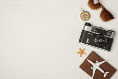 Güneş gözlüğünün üst görüntüsü pusula kamerası denizyıldızı ve uçak modeli izole edilmiş tahta arka planda solda boş alan ile pasaport kapağı üzerinde.