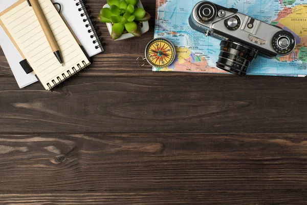 Haritadaki kamera ve pusula en üstteki görünüm fotoğrafı. Not defterleri. İzole edilmiş ahşap masa arkaplanındaki kalem fabrikası.