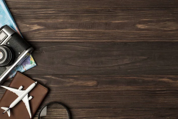 Pasaport kapağı büyüteç kamerası ve sağında telif alanı olan izole ahşap masa arkaplanındaki harita üzerindeki uçak modelinin üst görünümü